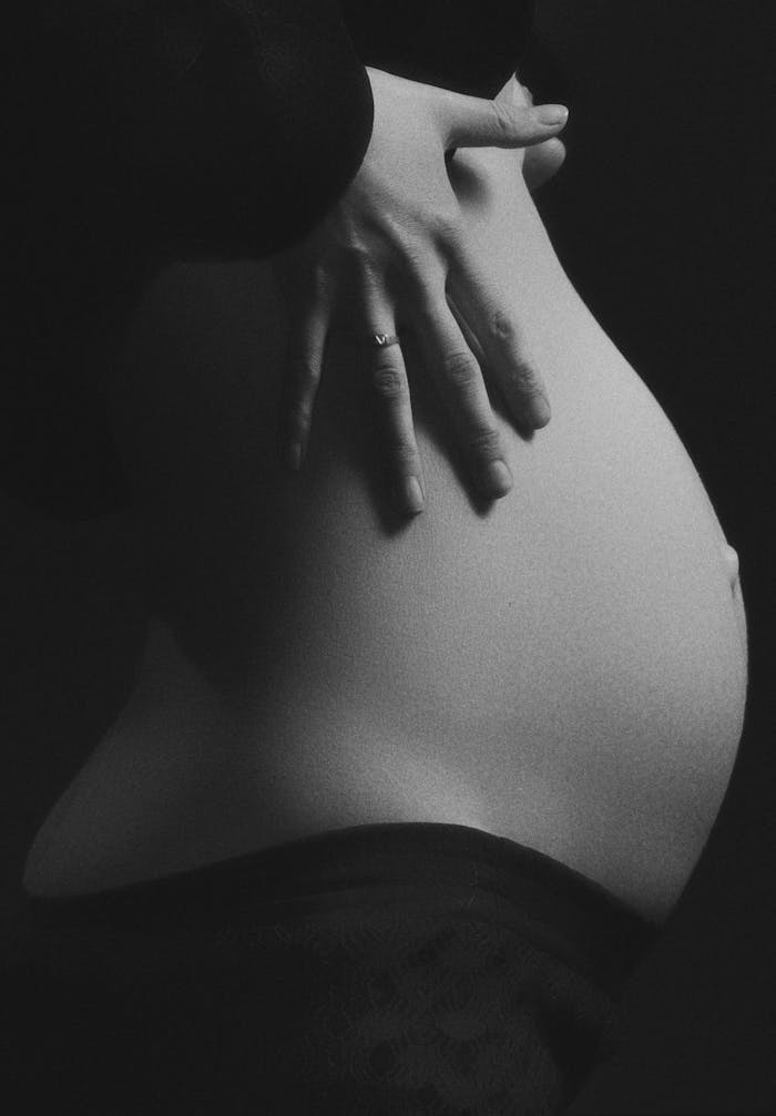 Intimate black and white photo of a pregnant womans belly with hand gently resting.